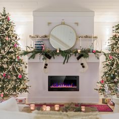 a living room decorated for christmas with stockings on the mantel and trees in front