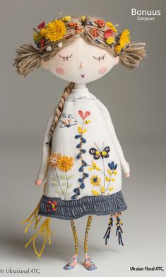 the doll is wearing a white dress with flowers on her head and braids in her hair