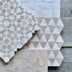 a wall made out of white and grey tiles with geometric designs on it's sides