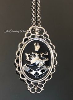 a silver and black pendant with a white dragon on it's back drop chain