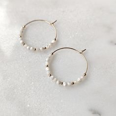 Elegant and minimalist Mother of Pearl hoop earrings! Pictures just do not do these gorgeous earrings justice. These gemstones have the most milky white color with stunning iridescence to them. When they are in the light, you can really see how dynamic they are. These are earrings you will want to wear over and over again. They are neutral enough for everyday wear. And they are the perfect earrings for your wedding day. They also have a coastal look to them, which makes them perfect for your bea Modern White Pearl Earrings For Everyday, White 14k Gold Filled Hoop Earrings, Modern White Pearl Hoop Earrings, Handmade White 14k Gold Filled Hoop Earrings, Handmade 14k Gold Filled White Hoop Earrings, Delicate White Hoop Earrings With Ear Wire, White Hypoallergenic Hoop Earrings, Hypoallergenic White Hoop Earrings, Nickel-free White Hoop Pearl Earrings