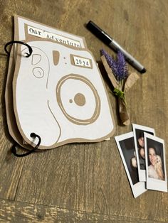 an old camera and some photos are on the table next to each other with a pen