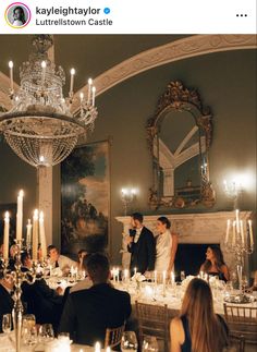 a bride and groom are standing in front of their guests at a dinner table with candles on the tables