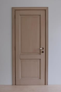 an empty room with a wooden door and white walls