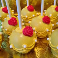 yellow cake pops with red roses and white candles on a gold plated tablecloth