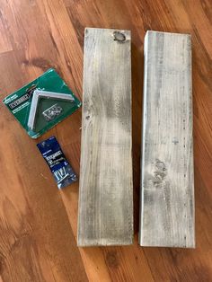 two pieces of wood sitting on top of a wooden floor next to a package of glue