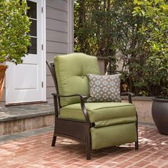 a green chair sitting on top of a brick patio next to a potted plant