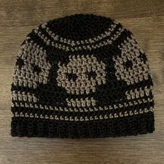 a crocheted skull and crossbone beanie on a wooden floor with wood background