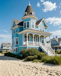 a blue and white house on the beach with stairs leading up to it's second story