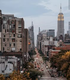 a city street filled with lots of traffic next to tall buildings and skyscrapers in the distance