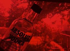 a bottle of vodka sitting on top of a window sill in front of a red sky