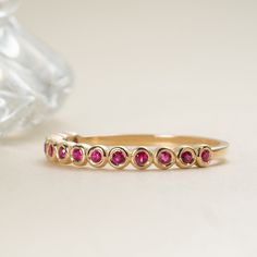 Arleth Ruby is a stone of royalty, highly coveted for its rich red hue. This can be your vibrant and unique wedding band, yet also the perfect dainty ring to add a pop of color to your solid gold ring stack. Rubies fill ½ of the band. Choose your metal and size, and we will make it custom for you. - Handmade- Solid Gold- Natural Ruby- Total Ruby Carat Weight: 0.19 ctw- Size of Band: 2.5 mm All pieces come beautifully boxed in suede pouches you can always use when traveling! Gold Ruby Ring With Half Eternity Design, Elegant Half Eternity Ruby Ring, 14k Gold Ruby Ring With Half Eternity Design, Gold Ruby Half Eternity Rings, 14k Gold Ruby Half Eternity Ring, Ruby Eternity Band, Ruby Band Ring, Ruby Wedding Band, Ruby Wedding Rings