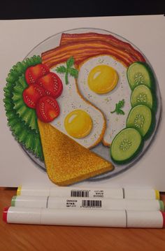 a plate with eggs, tomatoes and cucumbers on it next to marker pens