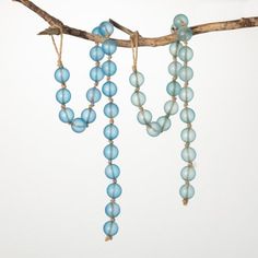 blue glass beads hang from a tree branch