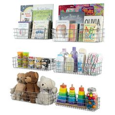 three metal baskets filled with toys and books on top of a white wall next to each other