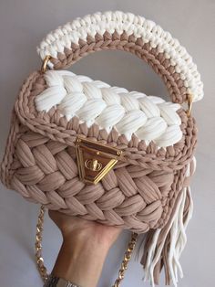 a hand holding a beige and white purse