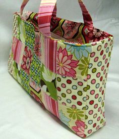 a multicolored bag with flowers on it sitting on a white tablecloth covered surface