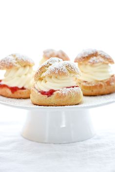 three pastries on a white cake plate with powdered sugar and strawberry fillings