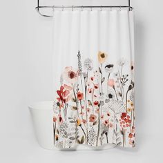 a shower curtain with flowers on it and a bowl next to it in the bathroom