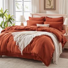 a bed with an orange comforter and pillows