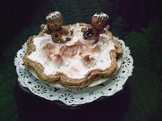 a cake on a doily topped with frosting and two small figurines