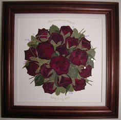 there is a framed painting with red roses in the center and green leaves on it