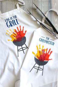 two aprons with the words king of the grill painted on them next to scissors