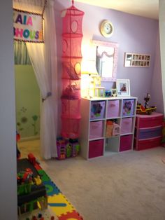 a child's bedroom with toys and decor in the corner, including pink storage bins