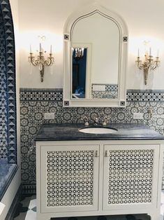 a bathroom with blue and white tiles on the walls, sink and mirror in it