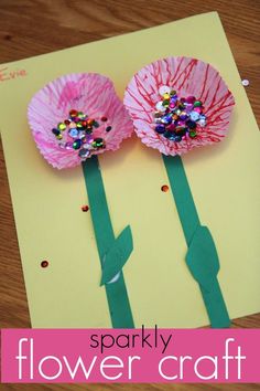 two paper flowers are sitting on top of a piece of craft paper with the words sparkly flower craft