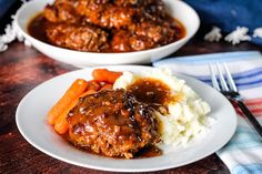 two white plates topped with meatballs and carrots next to mashed potatoes on a wooden table