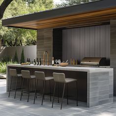 an outdoor kitchen with bar stools next to it