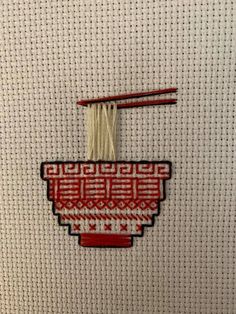 a red and white basket with noodles hanging from it's side on a wall