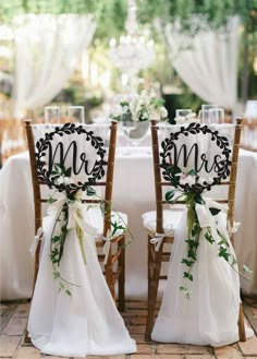 the chairs are decorated with flowers and monogrammed sashes for their guests to sit in