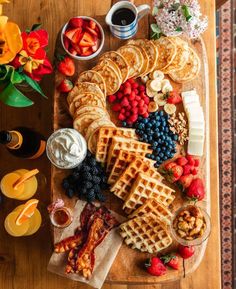 a wooden table topped with waffles, fruit and other foods on top of it