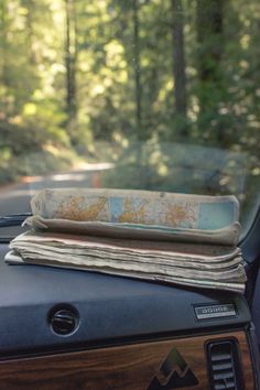 an old map is sitting on top of a car's dashboard in the woods