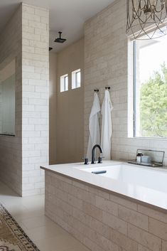 a bath room with a large tub and a sink next to a window in it