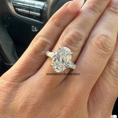 a woman's hand with a diamond ring on her finger, next to a car steering wheel