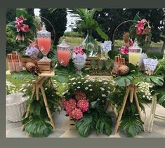 a table topped with lots of plants and flowers next to vases filled with drinks