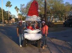 three people pose in front of a giant santa clause on the side of the road