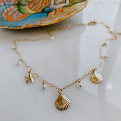 The Coast Trip Charm Necklace gives all the ocean vibes! Treasures from the sea- mini freshwater pearls plus charms of a starfish, clam shell and a sand dollar. Choose your length for the perfect fit! Available in 14k gold fill 16", 18" or 20" length available. Gold Starfish Shell Necklace With Starfish Charm, Gold Shell Necklace With Starfish Charm, Gold Shell Necklace With Starfish Charm For Vacation, Gold Charm Necklace With Star For Beach, Gold Star Charm Necklace For Beach, Gold Charm Necklace With Star Charm For Beach, Gold Starfish Shell For Beach, Gold Shell With Starfish Charm For Beach, Adjustable Gold Ocean-inspired Charm Necklace