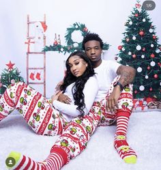 a man and woman sitting next to each other in matching christmas pajamas