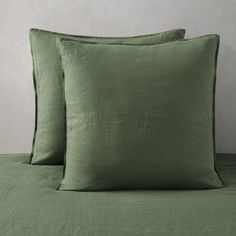 two green pillows sitting on top of a bed