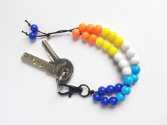 a multi - colored beaded bracelet with two keys