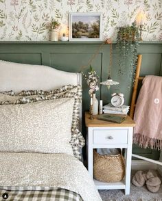 a white bed sitting next to a green wall with pictures on the wall above it