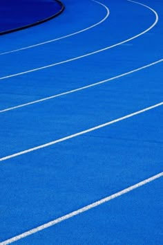 a man riding a skateboard on top of a blue race track with white lines