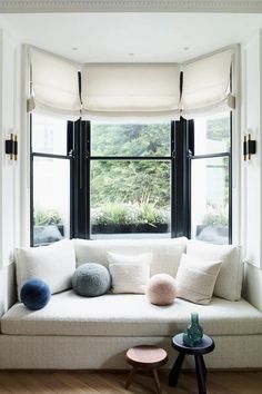 a white couch sitting under a window next to a table with two pom poms on it