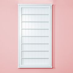 an empty white shelf against a pink wall