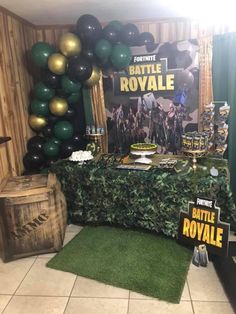 a table topped with balloons next to a green and gold balloon wall in a room