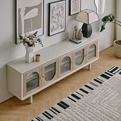 a living room with pictures on the wall and a rug in front of an entertainment center